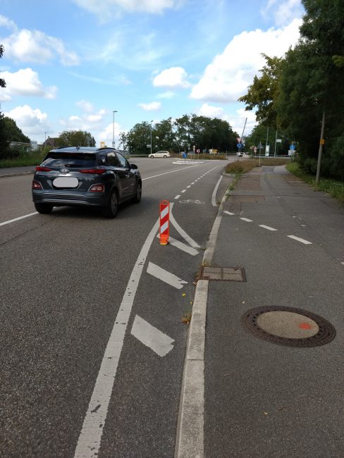 Abschnitt mit der Bischofsmütze, wo es auf die autobefahrene Straße zugeht. Gerade fährt ein Auto an der brenzligen Stelle vorbei.